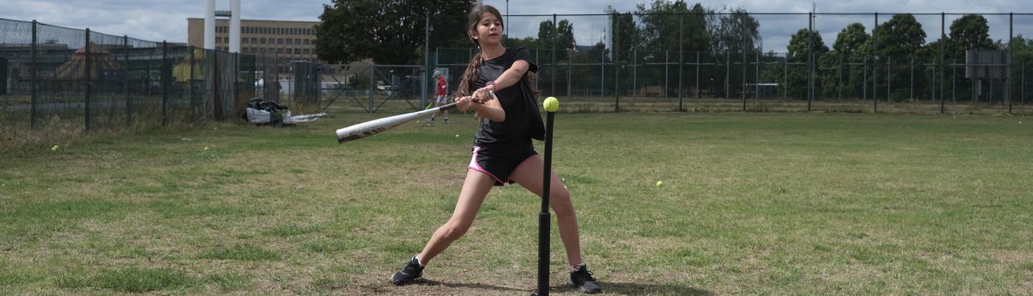 Jugendliches Mädchen macht Ballsport und schlägt ab beim Baseball in den Feriencamps für Teenager