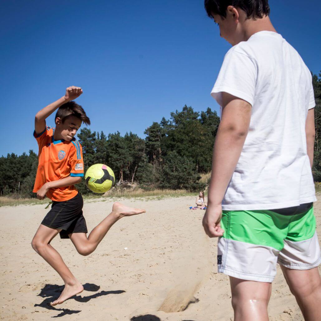 Kinder machen Ballsport und spielen in den Feriencamps am Strand Fußball