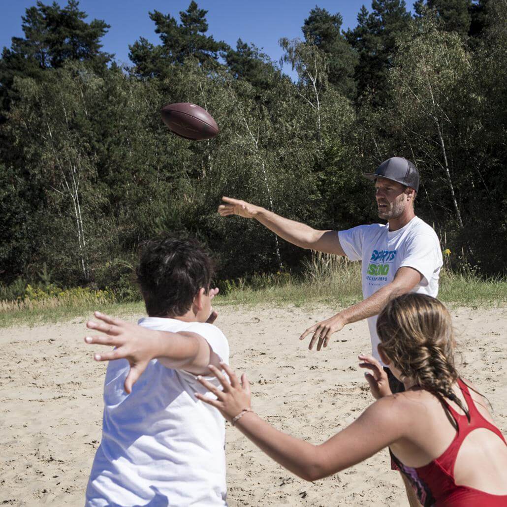 Kinder und Coach spielen Beach Rugby am Strand in den Feriencamps Wolfsburg