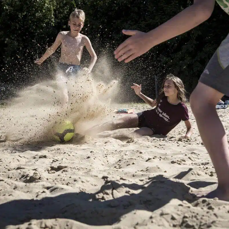 Teenager haben auf den Jugendreisen nach edem Surfen in den Wellen Beachfun am Sandstrand und spielen Fußball