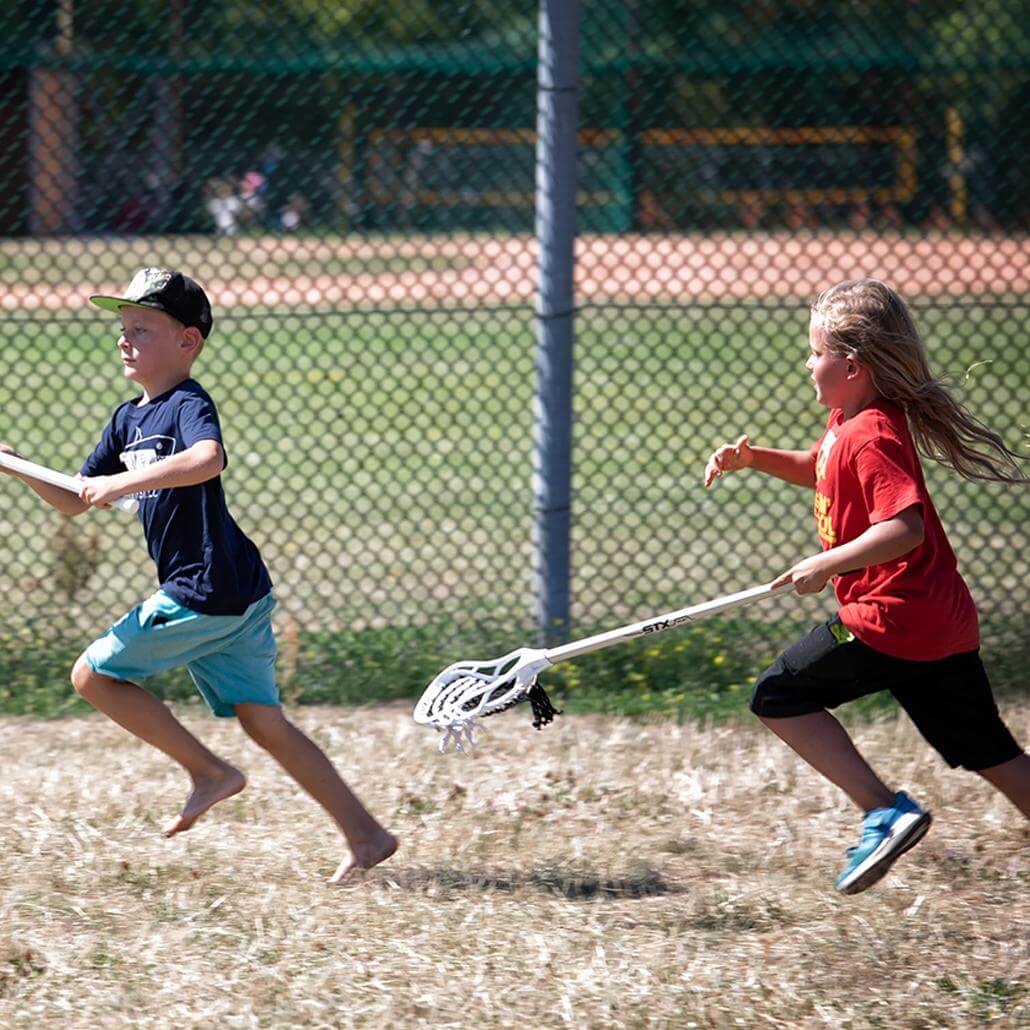Kinder rennen sich hinterher mit Lacrossschlägern in den Feriencamps Hamburg