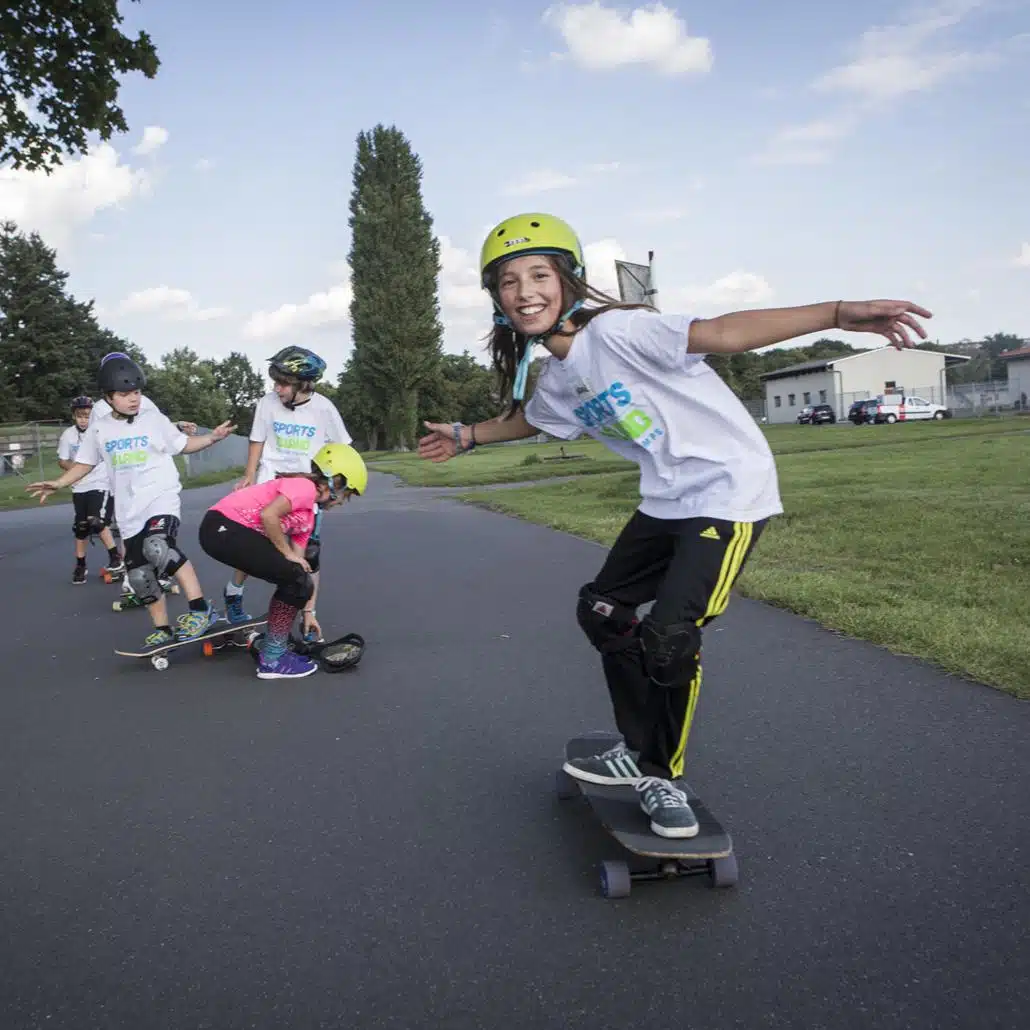 Kinder machen im Sportcamp Funsport und fahren Skateboard