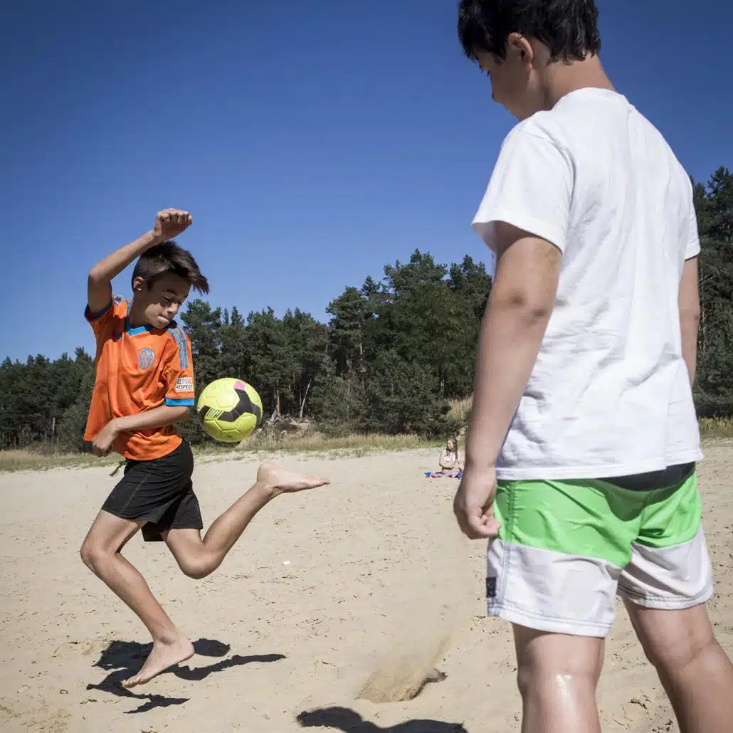 Zwei Kinder in den Feriencamps Potsdam spielen Fußball am Strand