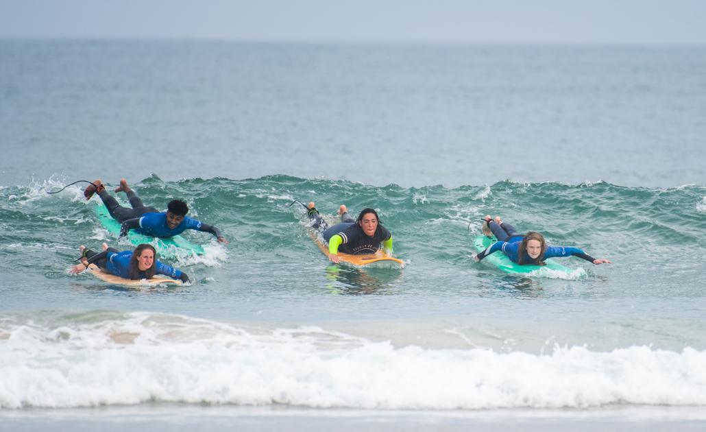 Teenager und Coach beim Surfen auf Jugendreisen paddeln an Land zum Essen