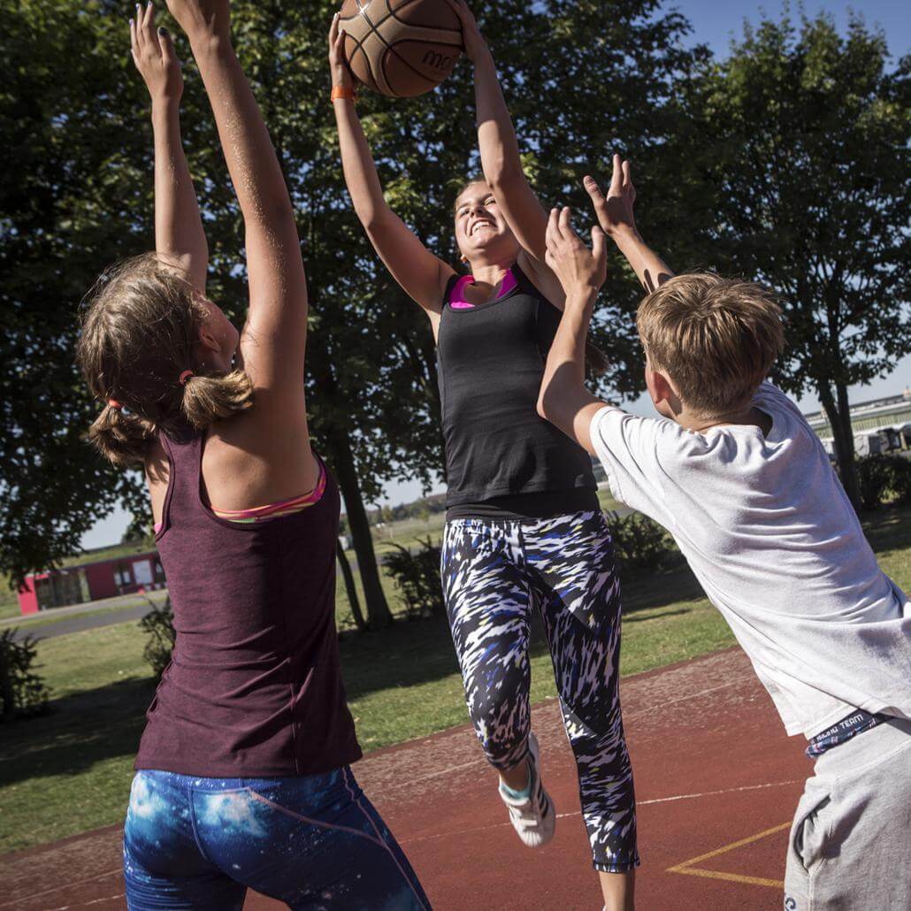 Kinder spielen Basketball in den Multisport Sommercamps