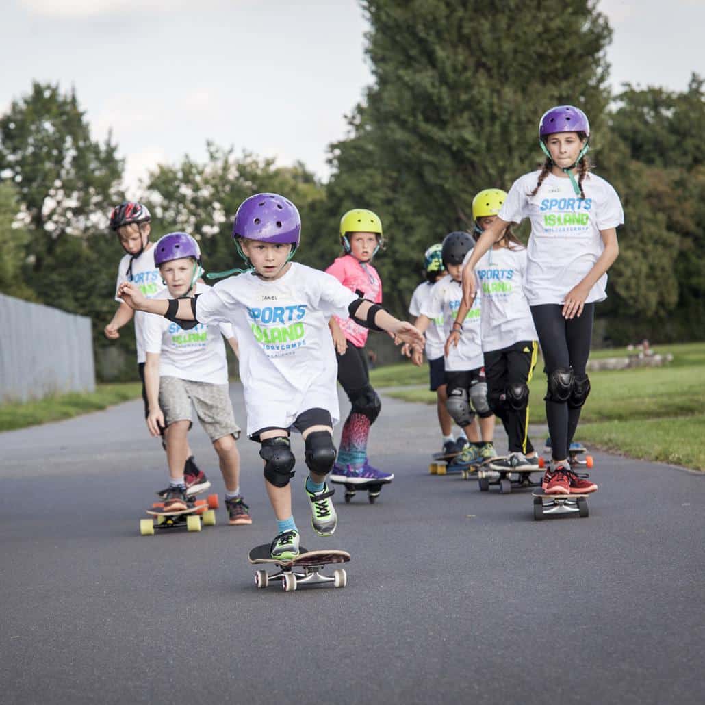 Kinder fahren Skateboard auf dem Tempelhofer Feld im Feriencamp Berlin