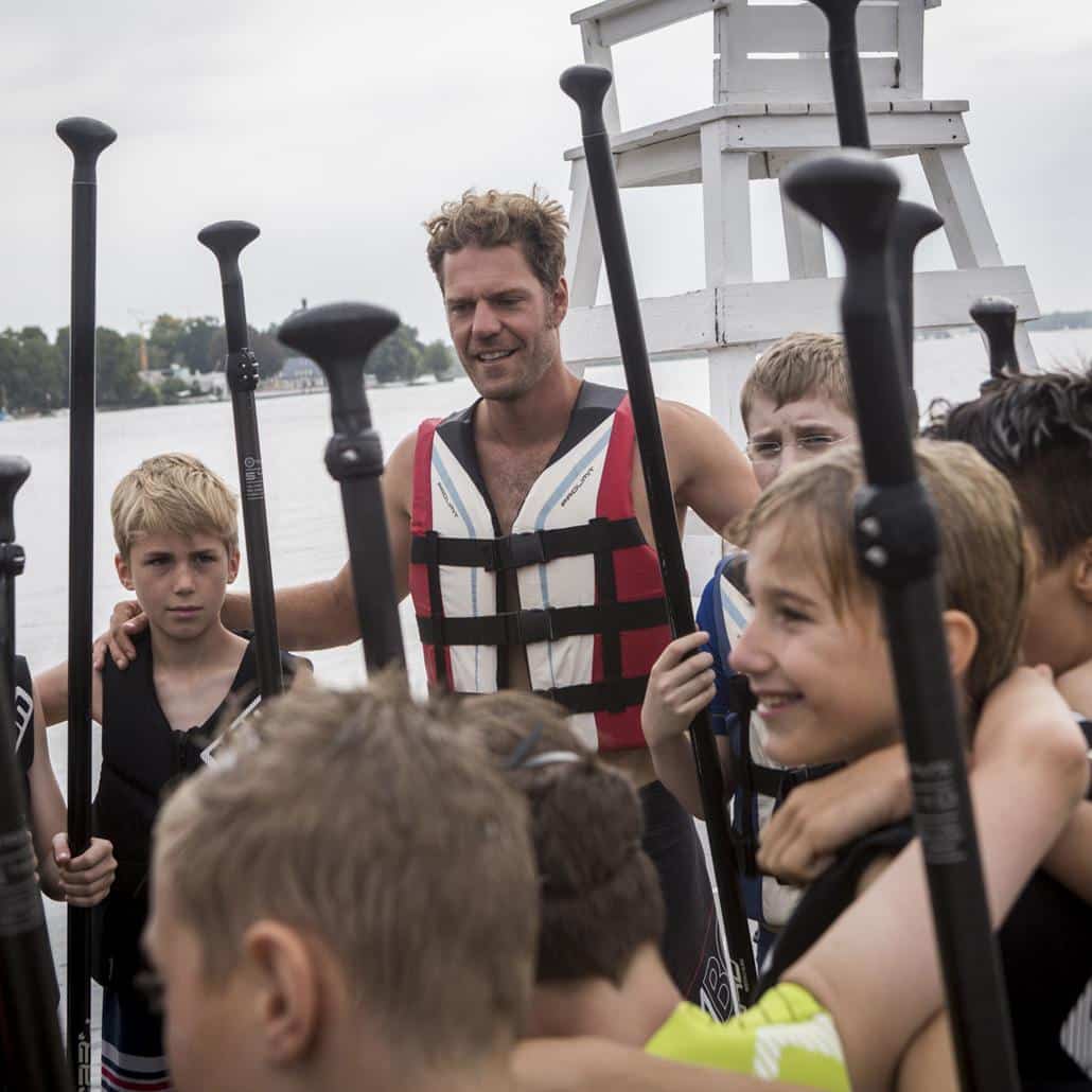 Kinder und Coach machen im Sportcamp eine Stand Up Paddling Tour