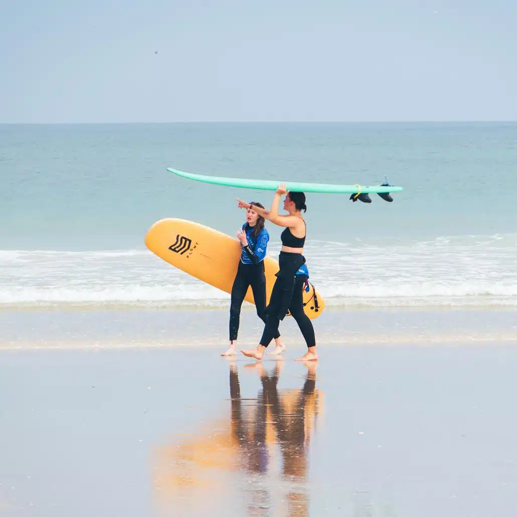 Jugendliche mit Surfbrett unter dem Arm am Strand in Portugal nach dem Surfkurs in den Feriencamps für Teenager.