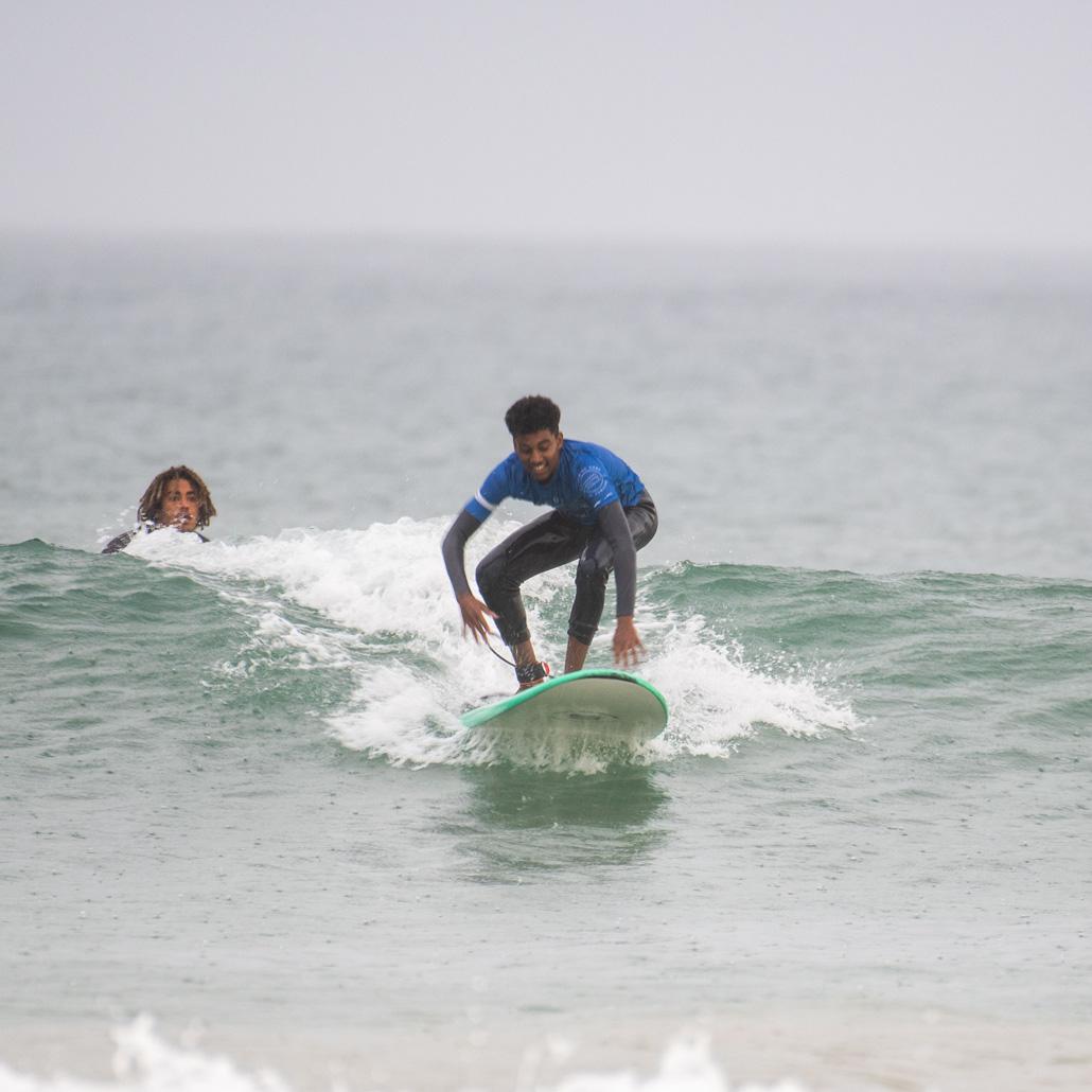 Jugendlicher mit Coach währnd des Surfkurses auf dem Surfbrett in den Surfcamps Portugal