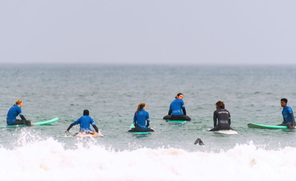 Jugendliche & Coach beim Surfen auf der Jugendreise zu Ostern, paddeln auf den Boards aufs Meer raus