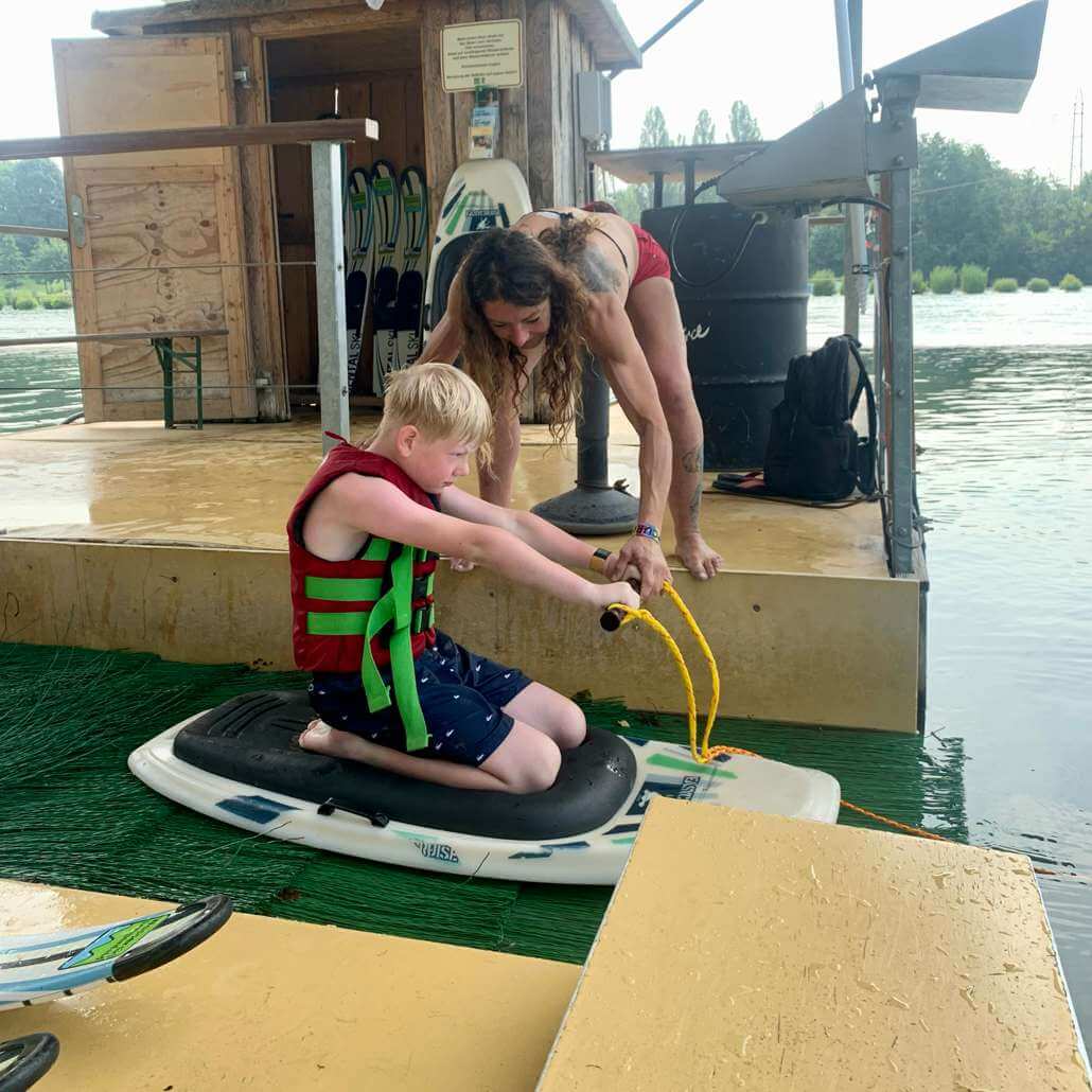 Coach hilft Kind vor dem Start auf dem Board beim Wassersport & Multisport im Sommercamps Köln #6