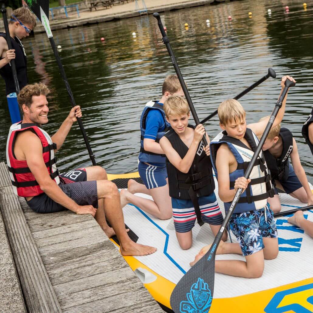 Kinder und Coach in den Sommercamps beim Wassersport bereit für die Stand Up Paddling Tour